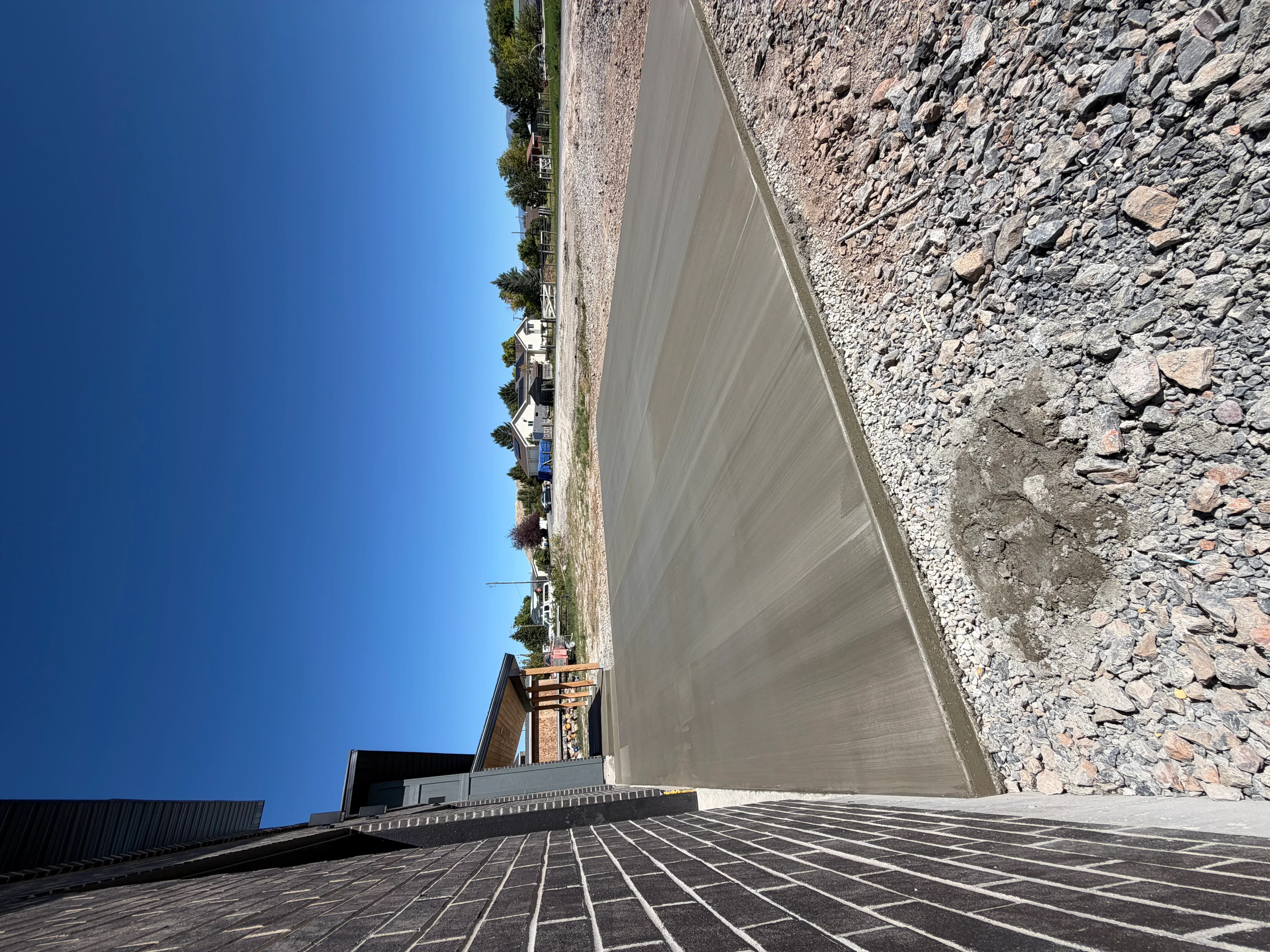 Concrete driveway with grid pattern and tall concrete retaining wall with stone backfill