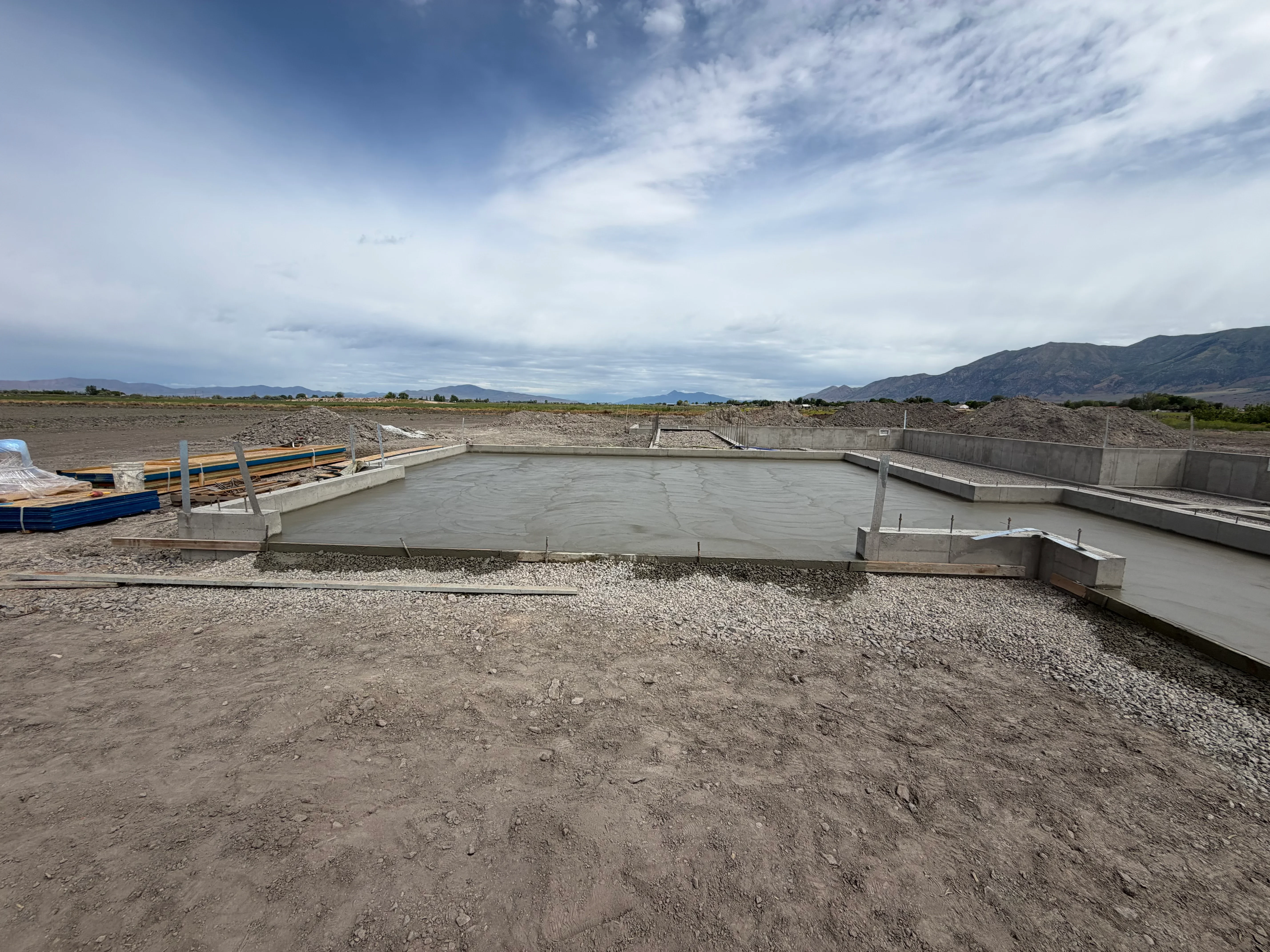 Concrete foundation with retaining walls, steel reinforcement, and wooden formwork on gravel base