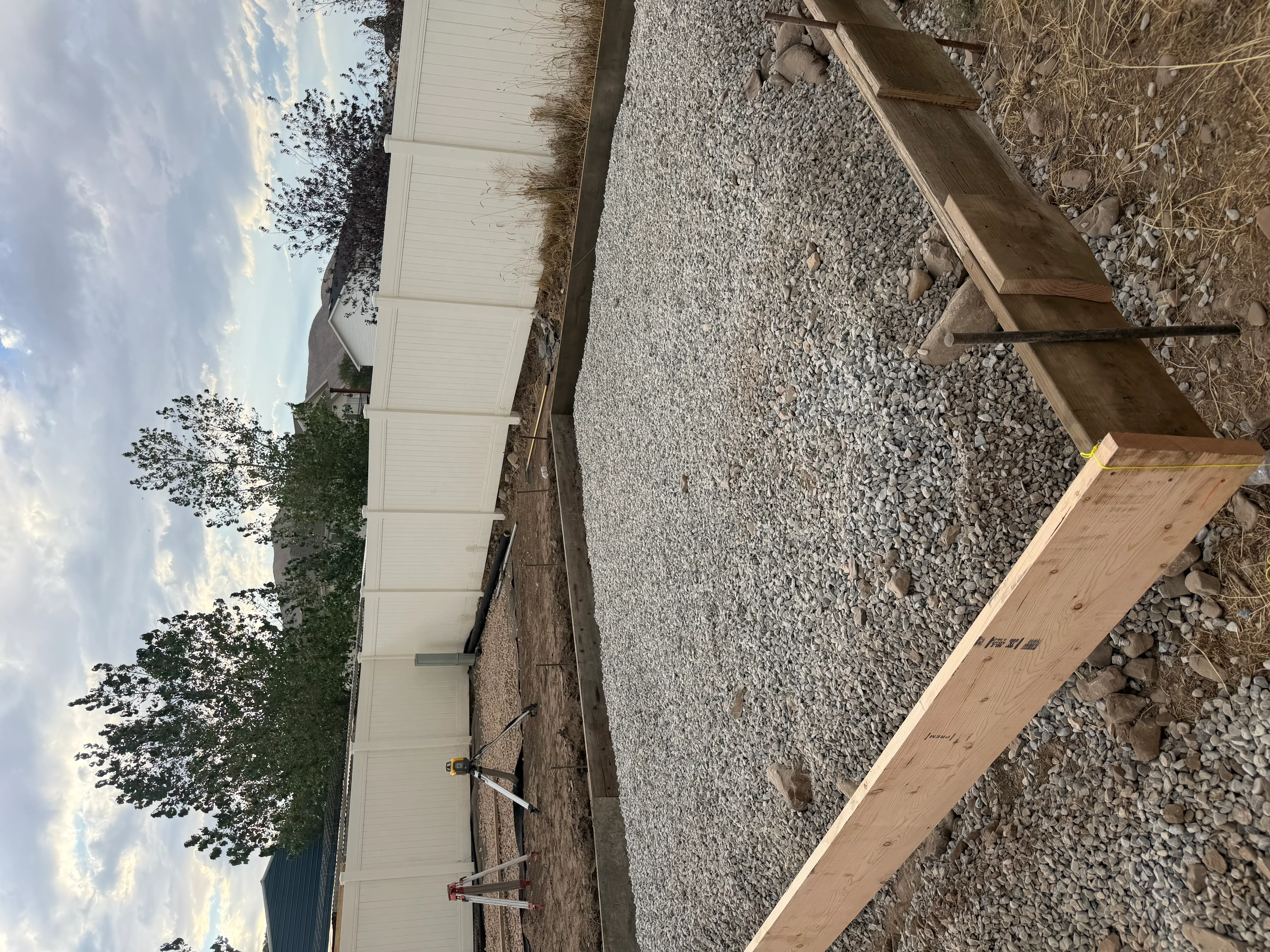 Newly poured concrete driveway with gravel base and wooden forms during installation
