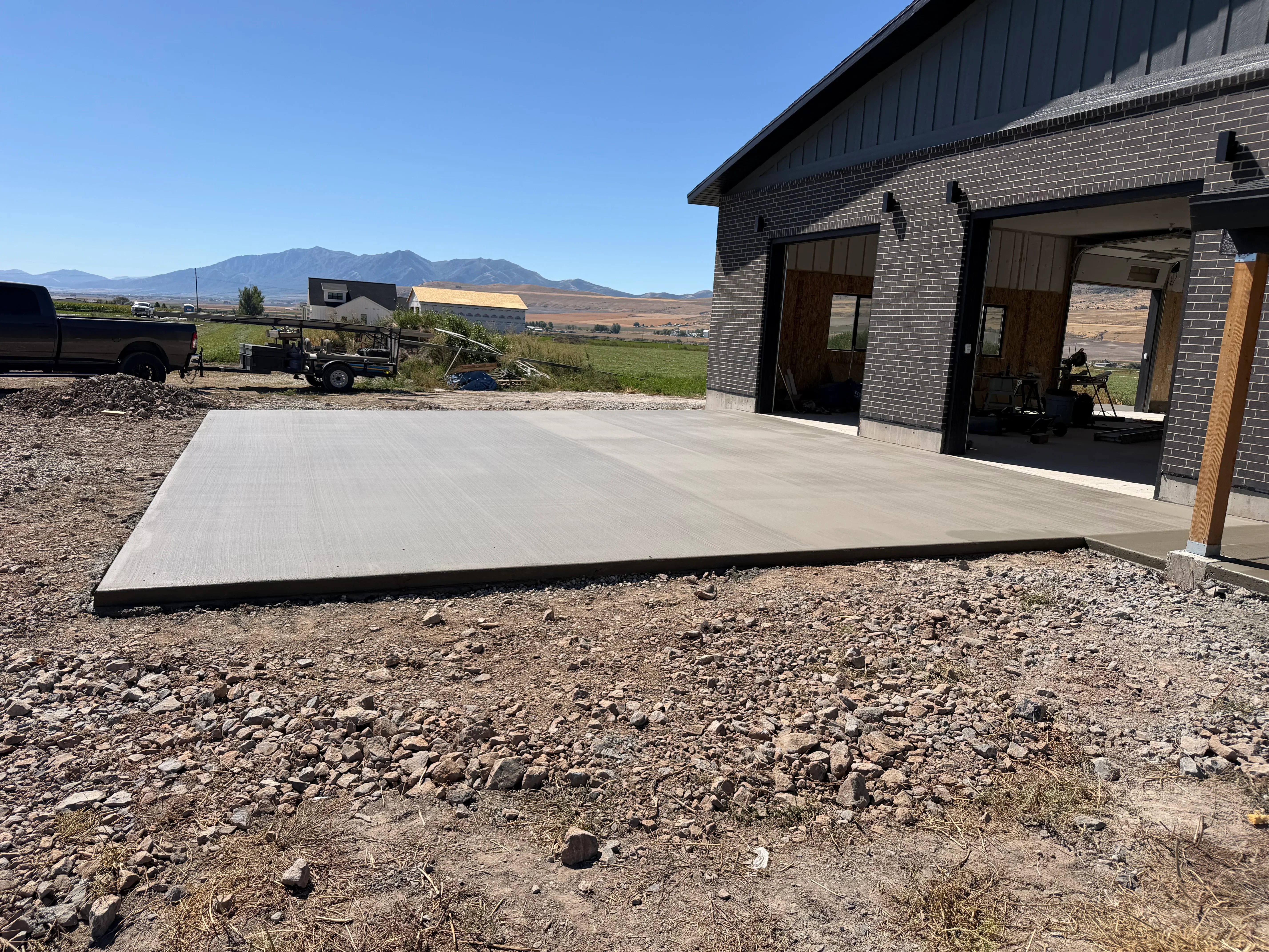 Light gray brushed concrete patio with clean edges installed next to brick home