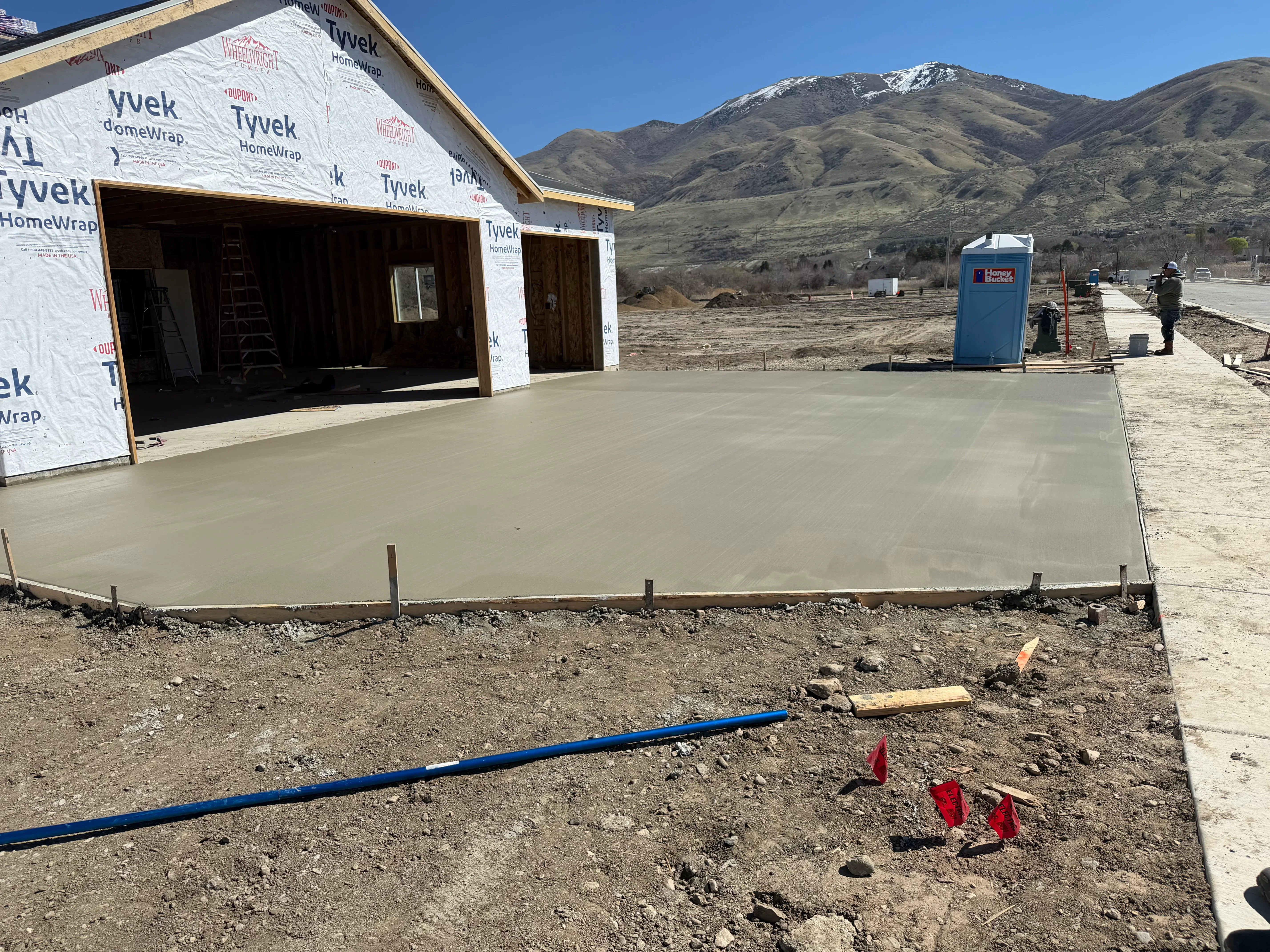 Freshly poured concrete foundation slab with edge forms and control lines on prepared ground