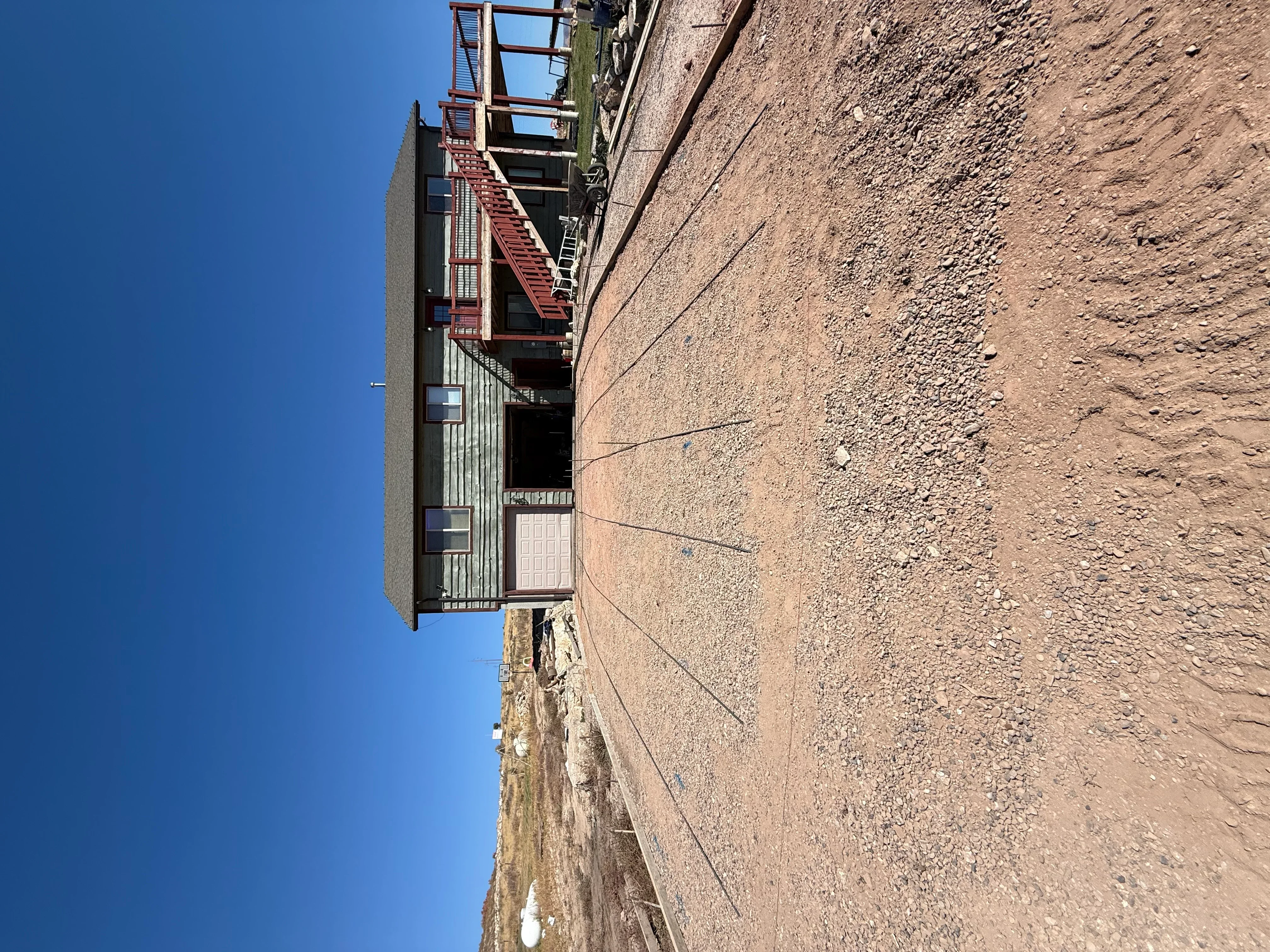 Concrete foundation pad with metal stairs, grading, and utility lines on cleared site