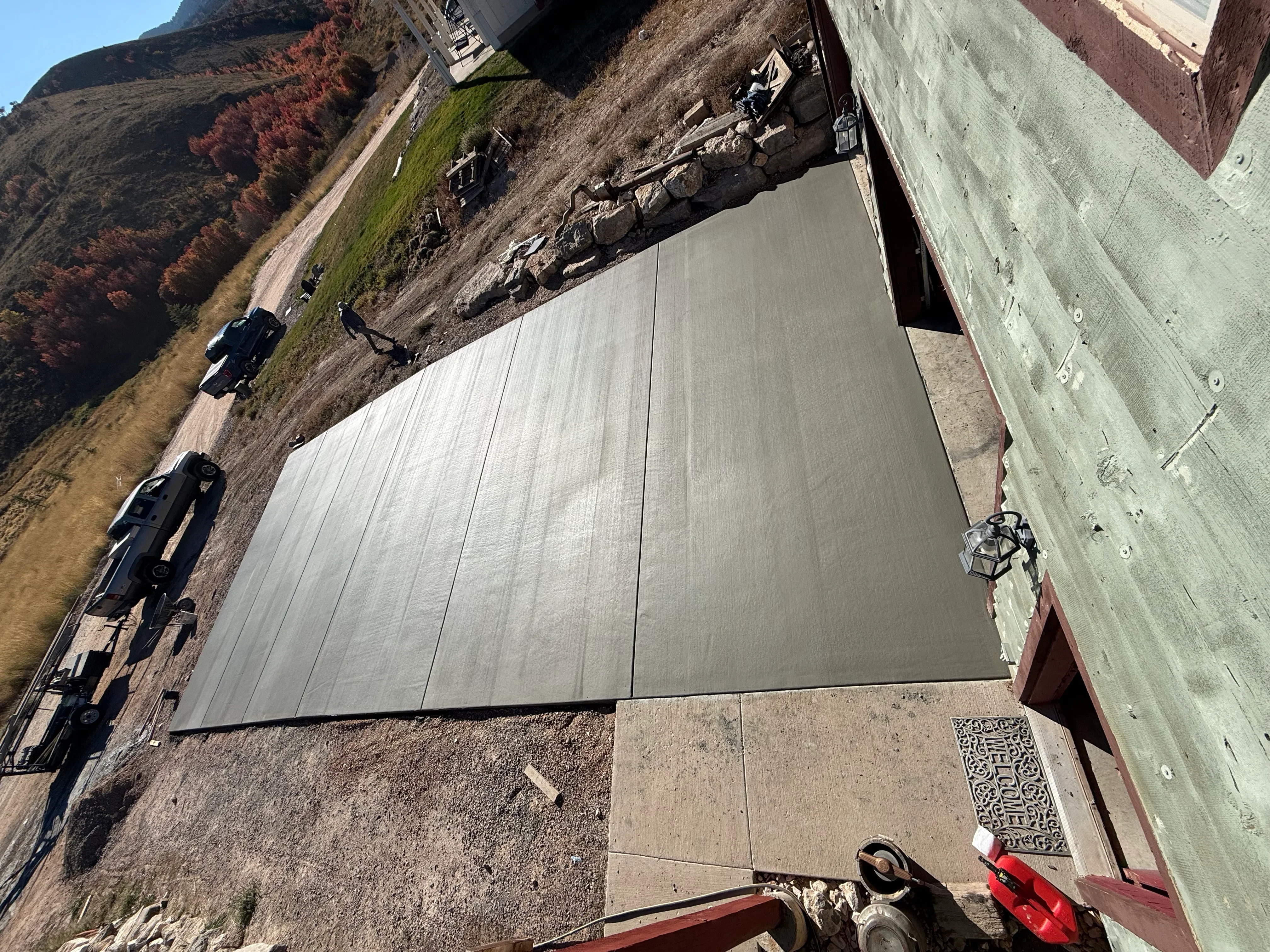 Finished concrete driveway with smooth troweled surface and formed edges on sloped terrain