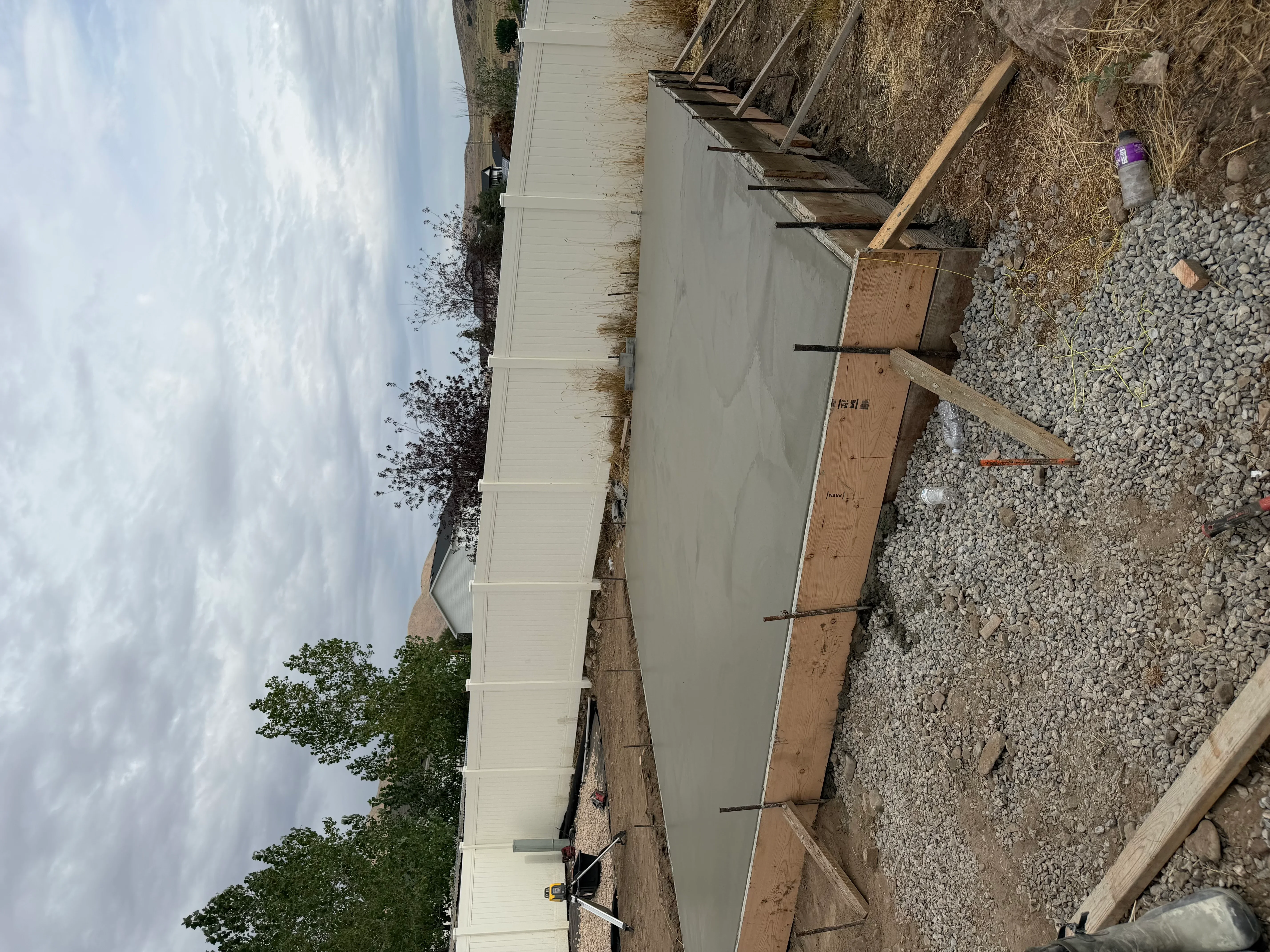 Fresh concrete driveway with wooden forms, gravel base, and control joints during installation